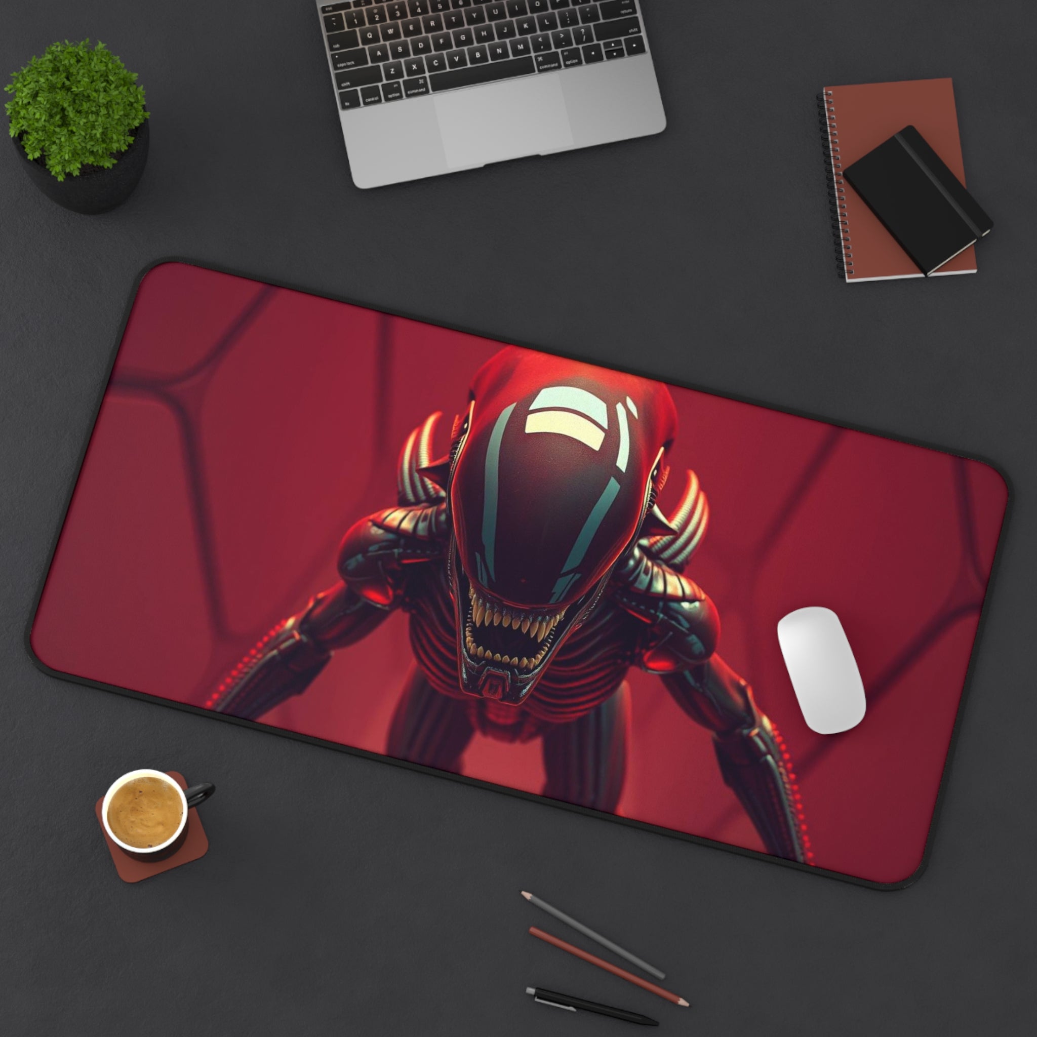 Desk setup with a large mouse pad featuring a robot design, laptop, phone, and coffee cup.