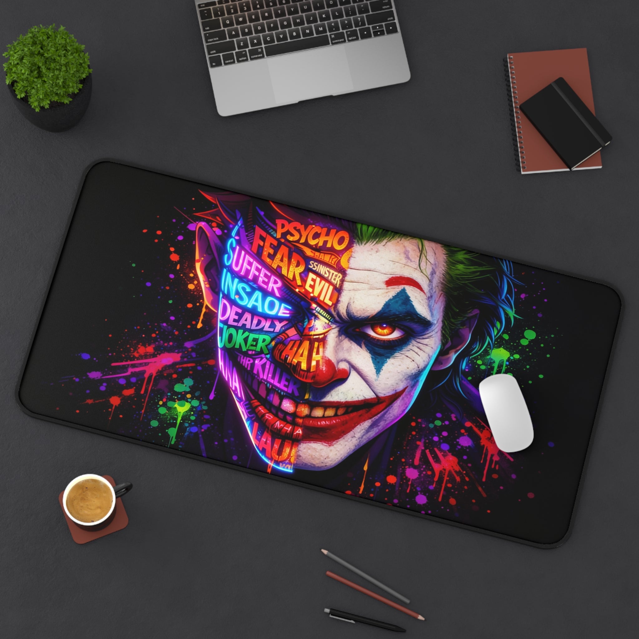 Joker-themed mouse pad on a desk with laptop, cup, and stationery items.