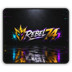 Rebel74 gaming mouse pad with a gold and silver logo, lightning emblem, and cyan and magenta accents on a black reflective background.