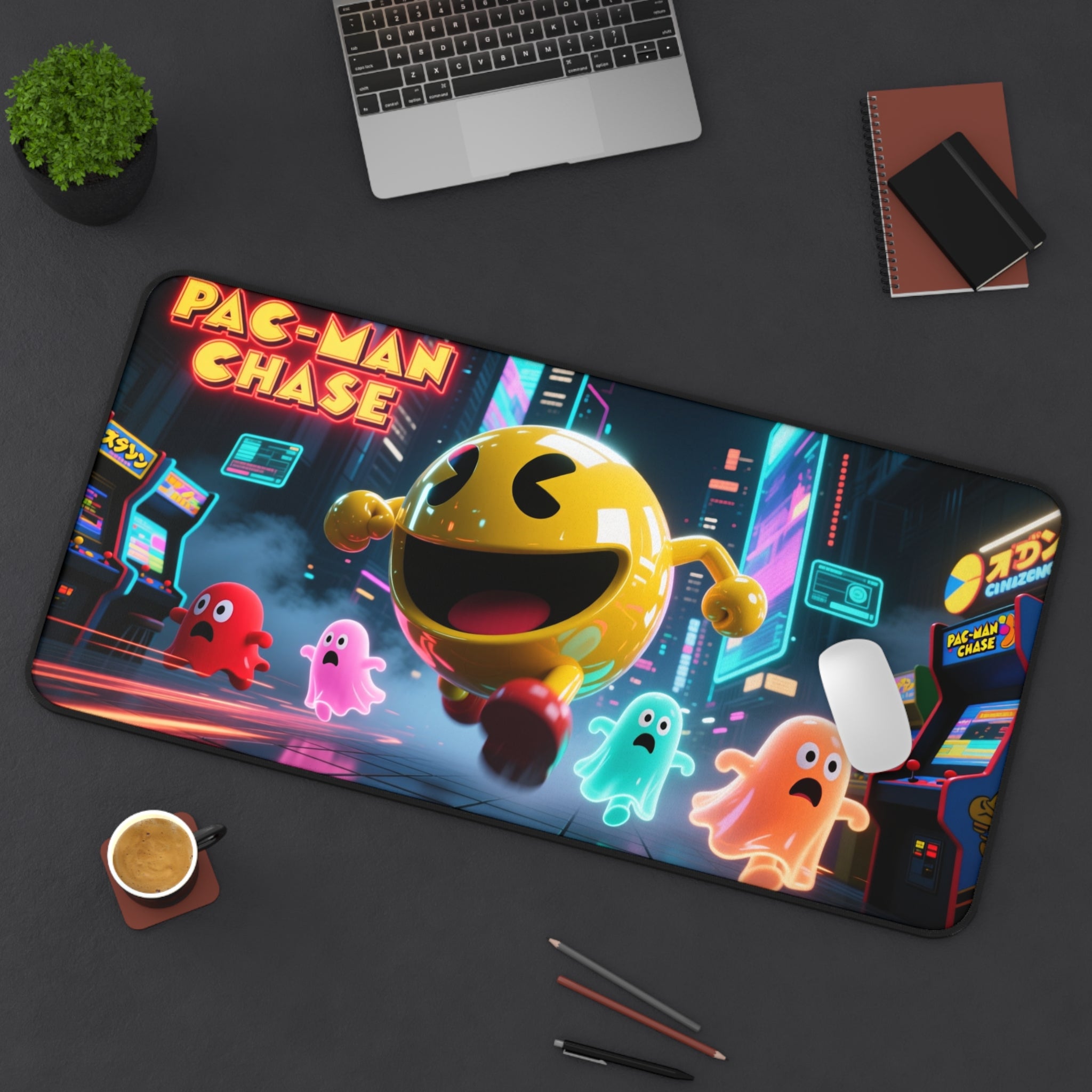 Pac-Man Chase desk mat on a dark surface with a laptop, coffee, and pens.