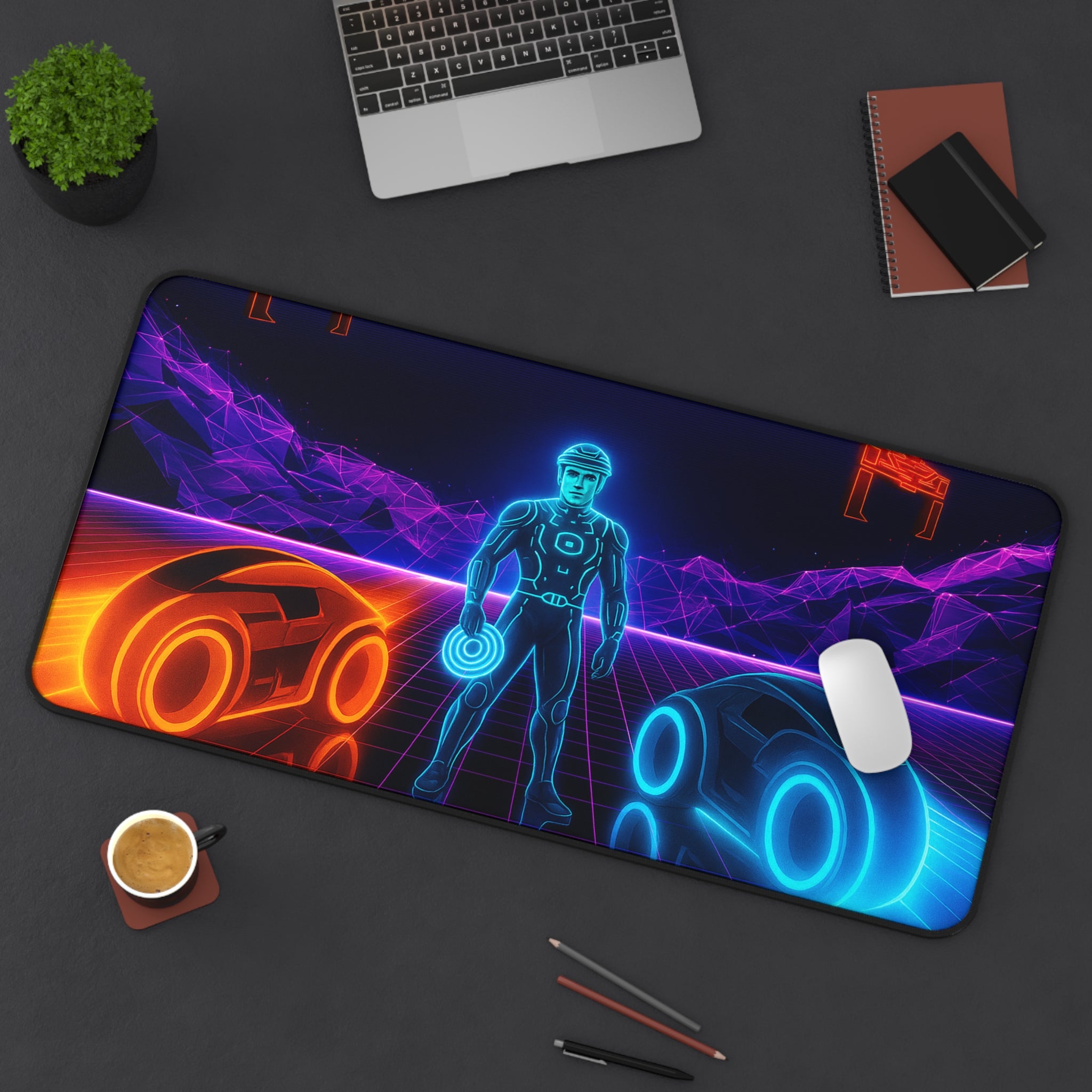 Gaming mouse pad with futuristic design on a desk with laptop, cup, and pens.